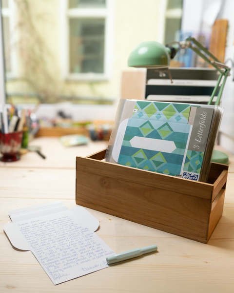 Three blue jacquard design letterfolds and an open letterfold arranged in a stylish stationery desk setting.