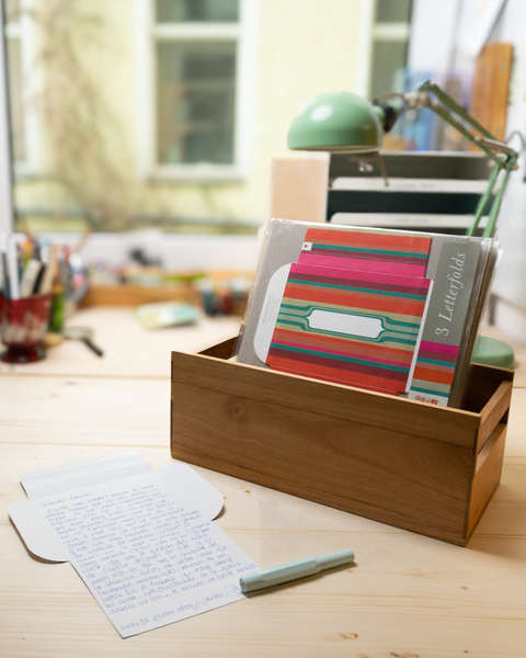 Three pink stripes letterfolds and an open letterfold arranged in a stylish stationery desk setting.
