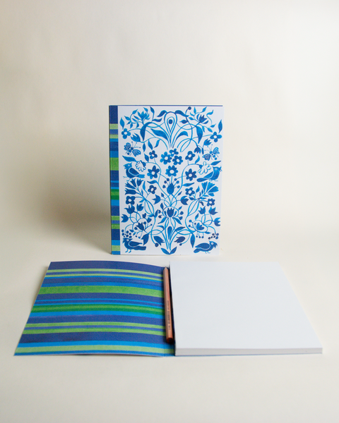 A5 notebook featuring a colorful garden and stripes in blue design, shown from the front and open to reveal its interior.