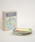 Bundle box of 9 numbered DIN A6 notebooks made from 100% recycled paper, eco-friendly and hand-bound, front view.