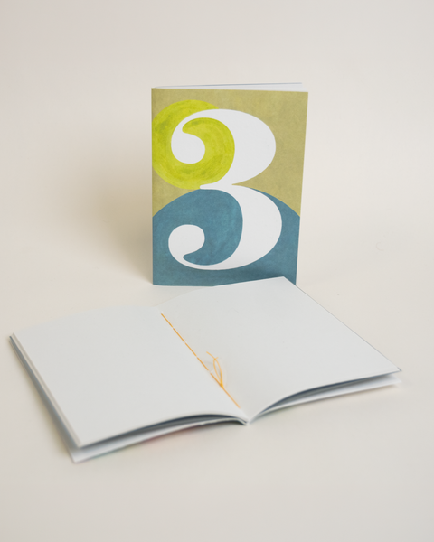 Eco-friendly notebook number 3, angled view, DIN A6 recycled paper cover, handmade in Berlin
